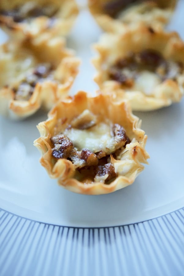 Pastry shells filled with Brie on a plate. 