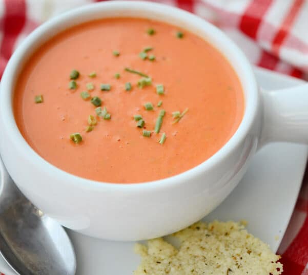 tomato soup in a white crock with a spoon
