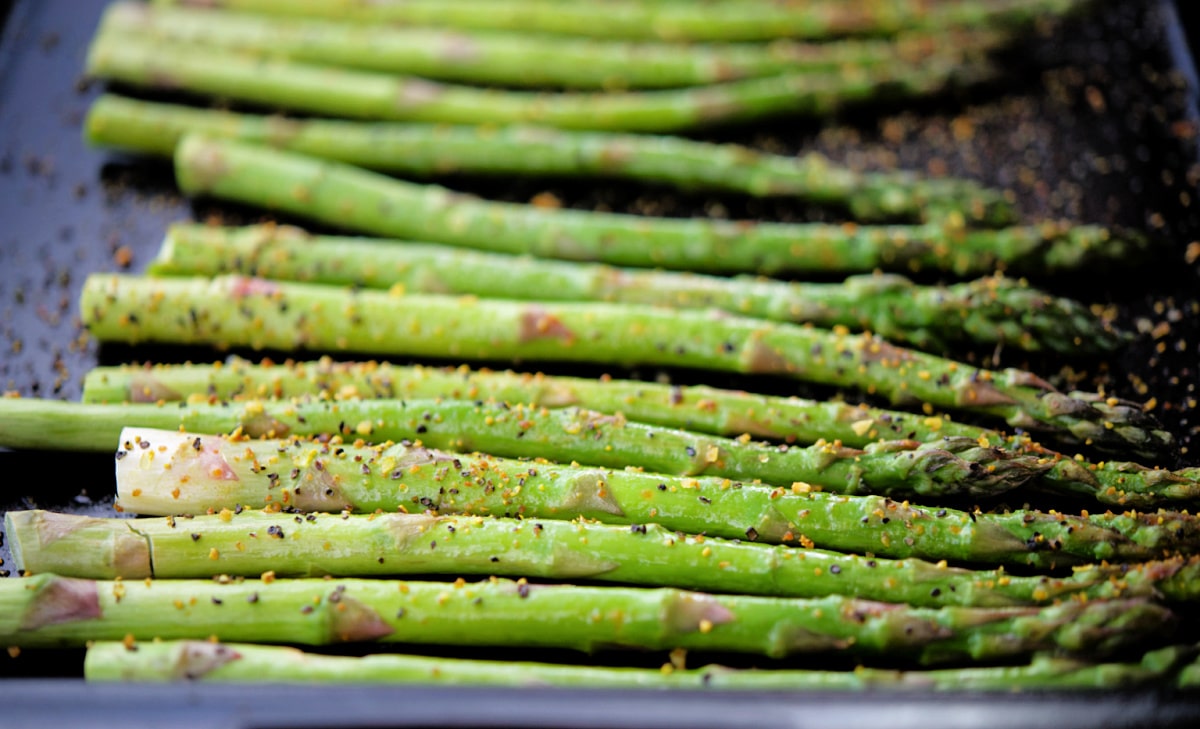 a close up of roasted asparagus with lemon pepper seasoning