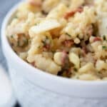 a close up of risotto in a white bowl with corn and bacon