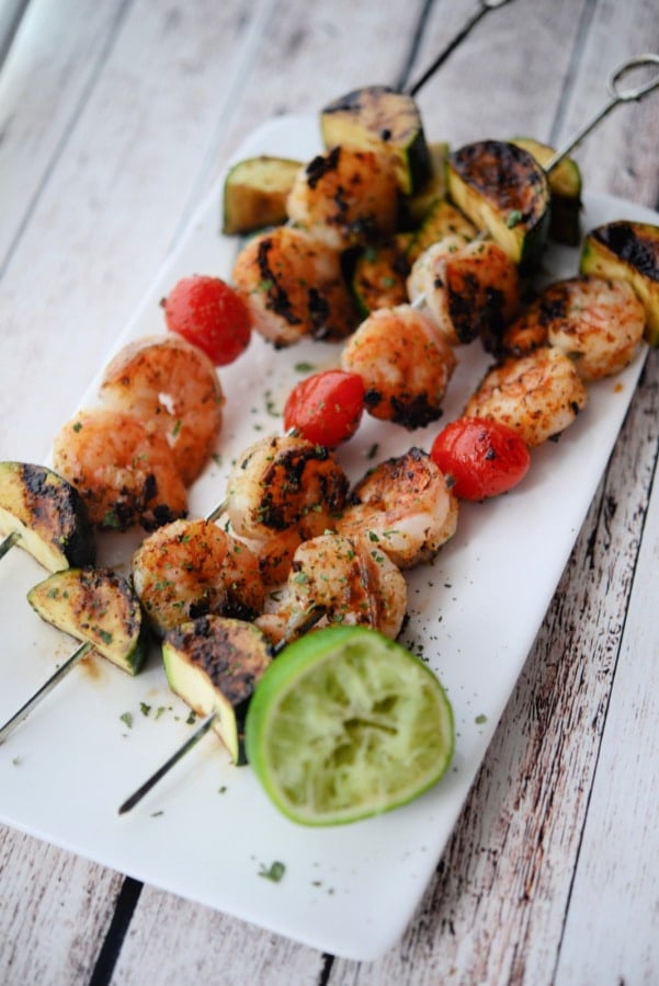 shrimp skewers with vegetables on a white plate