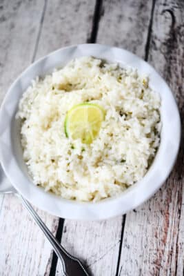 white rice in a white bowl on wood surface
