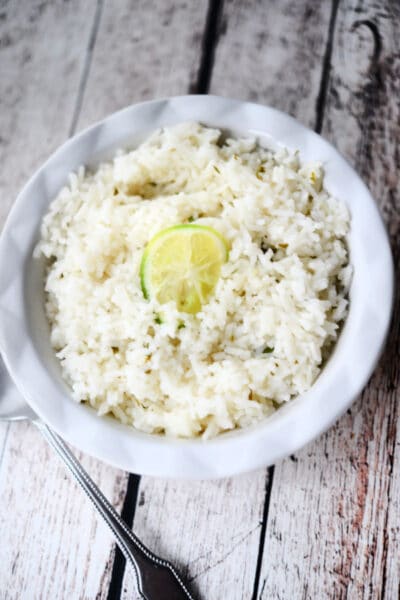 white rice in a white bowl on wood surface