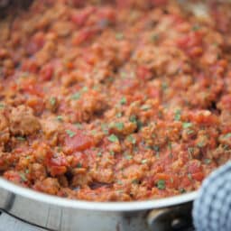 a close up of sauce with sausage in a pan