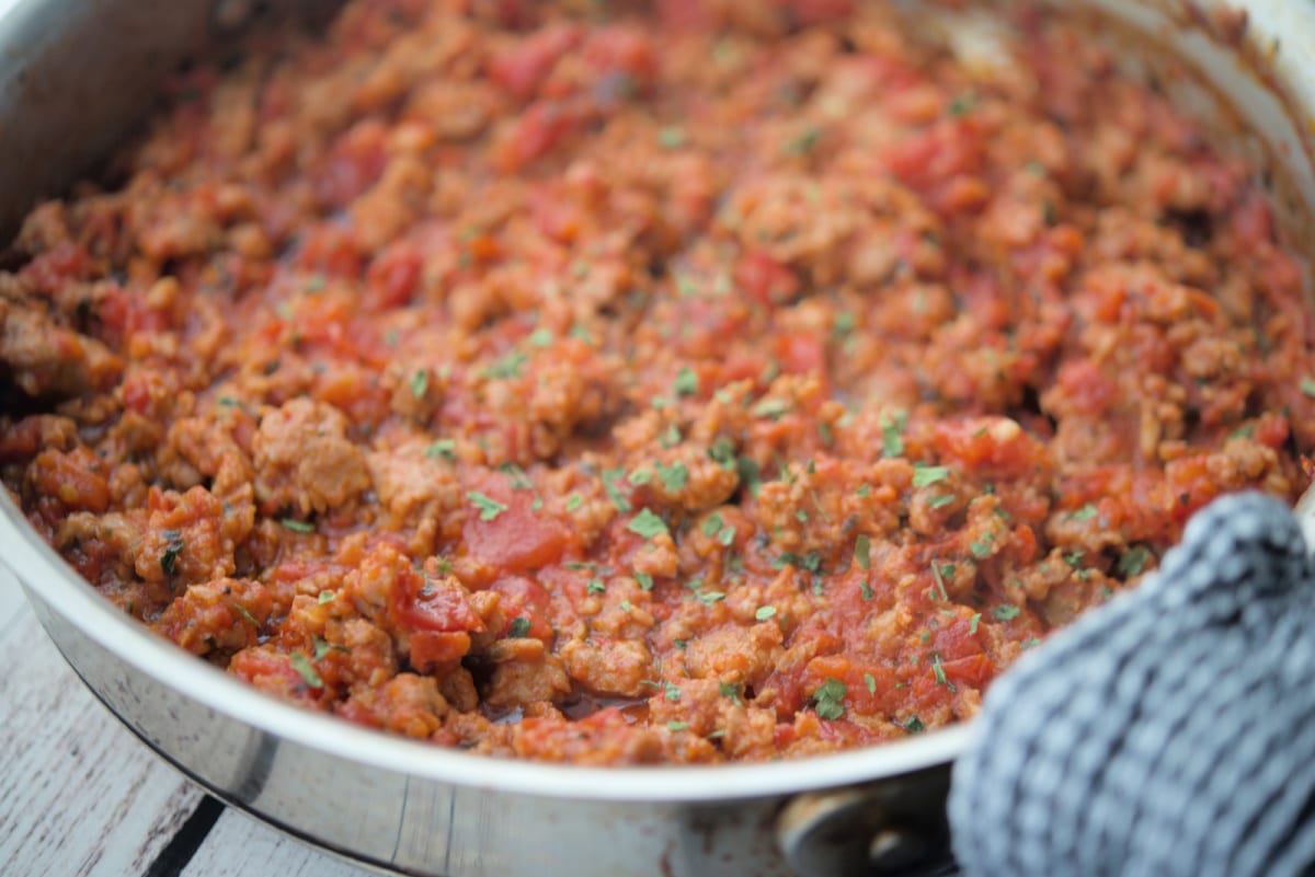 a close up of sauce with sausage in a pan