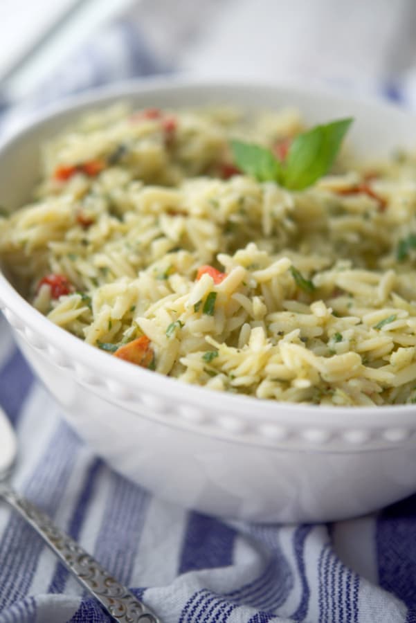 a white bowl with artichoke pesto pasta salad