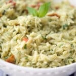 a close up of orzo salad in a white bowl