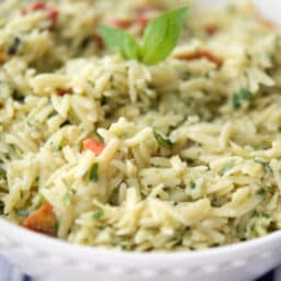a close up of orzo salad in a white bowl