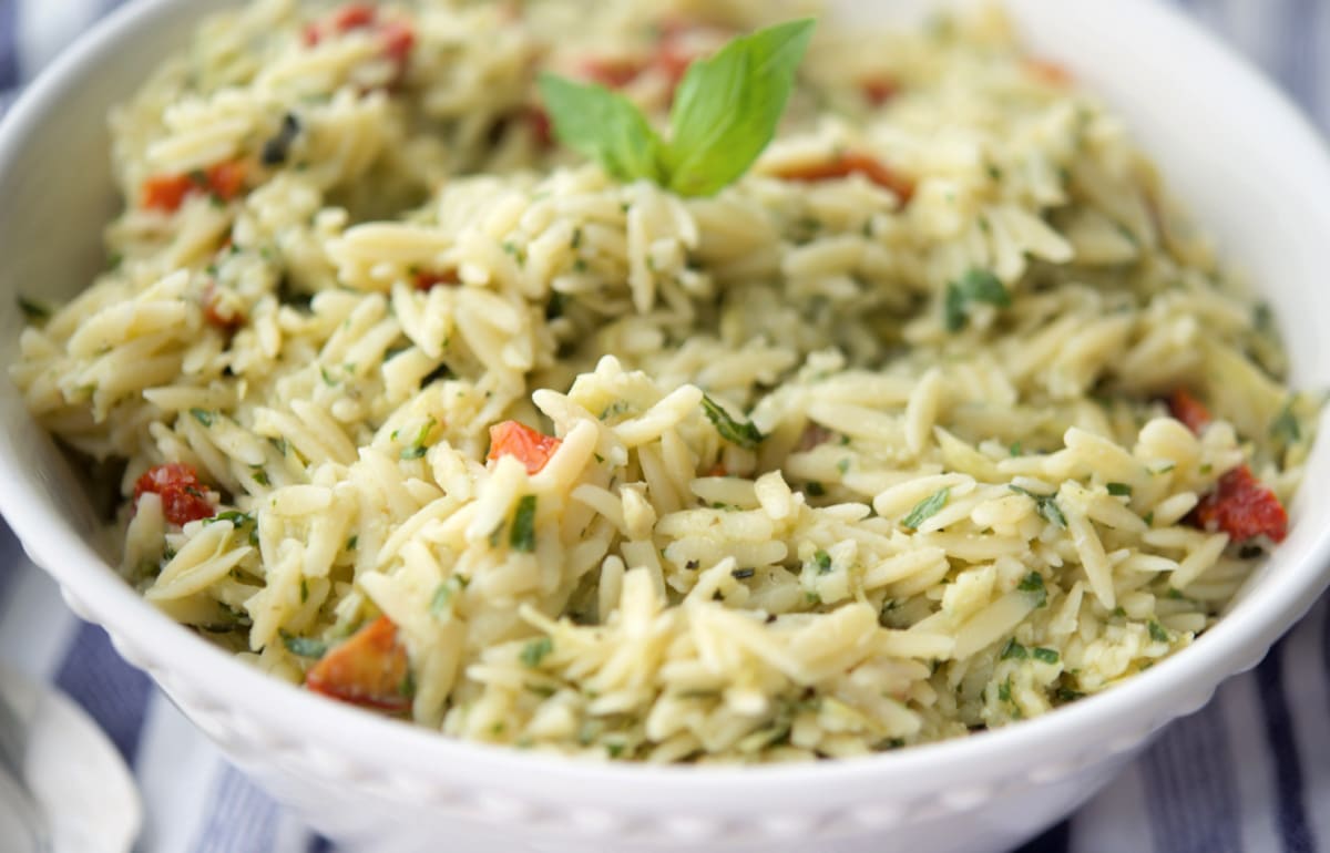 a close up of orzo salad in a white bowl