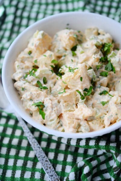 potato salad in a white bowl with a spoon