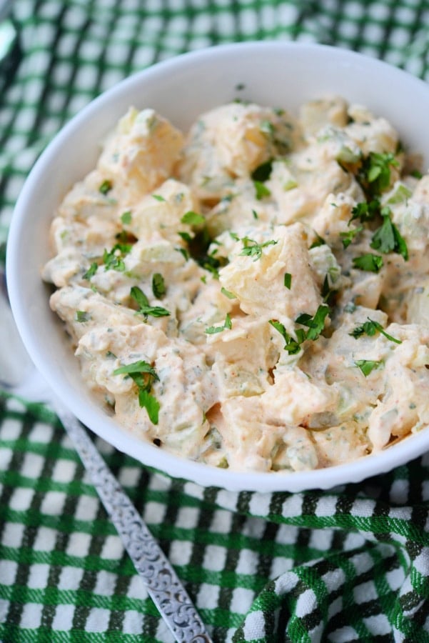 potato salad in a white bowl with a spoon