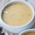 corn tomato chowder in a white soup bowl on a wooden board