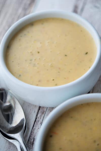 creamy corn tomato chowder in a white soup crock with spoons