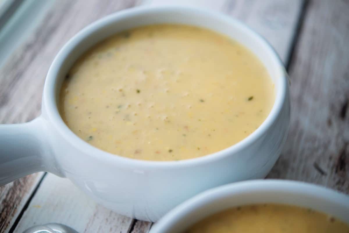 a close up of corn soup in a white crock