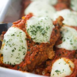 a close up of vodka sauce on breaded chicken in a dish