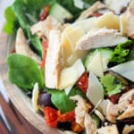 a close up of grilled chicken on top of a salad in a wooden bowl