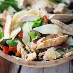 a close up of salad in a bowl with chicken and cheese