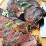 cooked sliced steak on a wooden cutting board