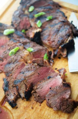 sliced rib eye steak on a wooden cutting board