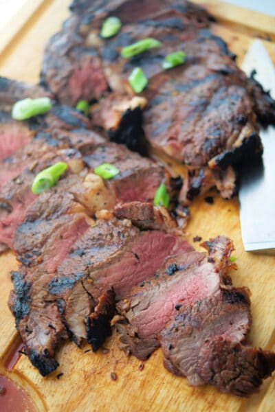 sliced rib eye steak on a wooden cutting board