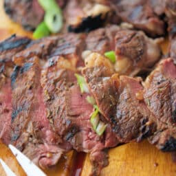 a close up of sliced steak on a wooden board