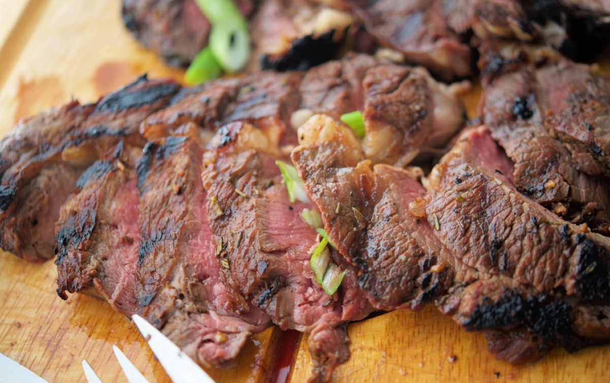 a close up of sliced steak on a wooden board