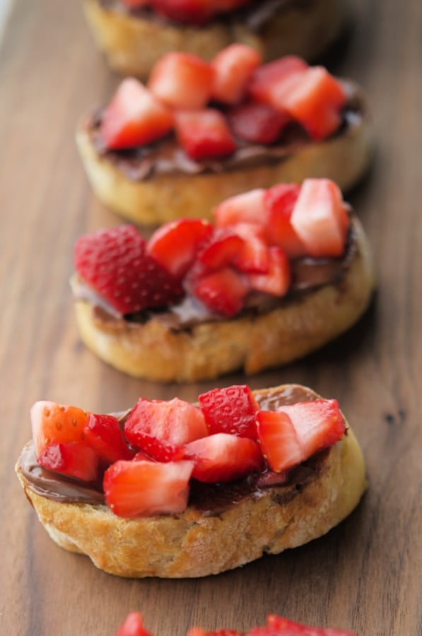 three crostini with strawberries and hazelnut spread on them