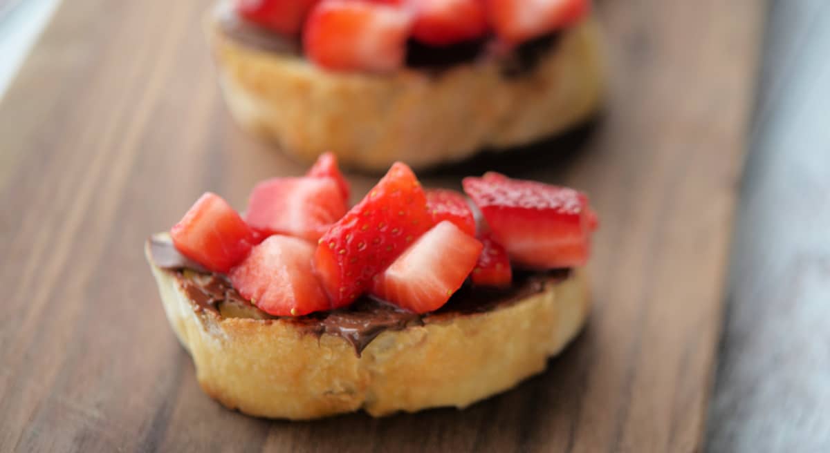 a close up of strawberries and hazelnut spread on bread