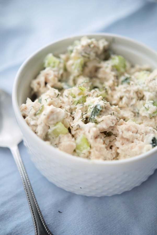 a bowl of chicken salad on a napkin with a spoon