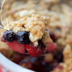 apple blueberry crisp in a white dish on a spooon