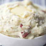 a close up of mashed potatoes in a white bowl with butter melting