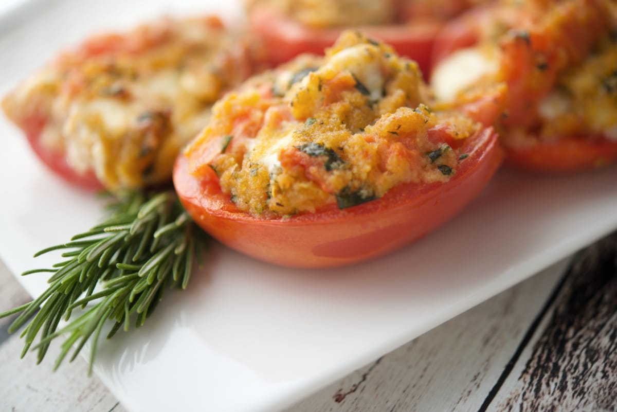 a close up of tomatoes on a plate with fontina cheese