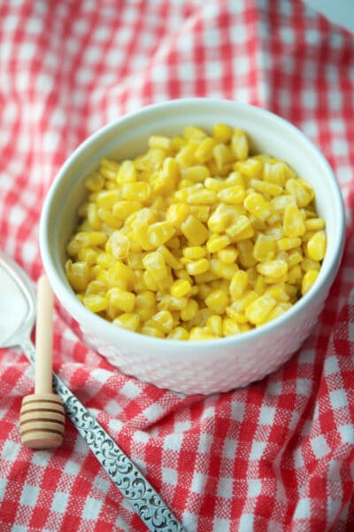 corn kernels in a white bowl on a plaid red and white napkin