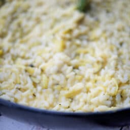 a close up of risotto with lemon and zucchini in a pan