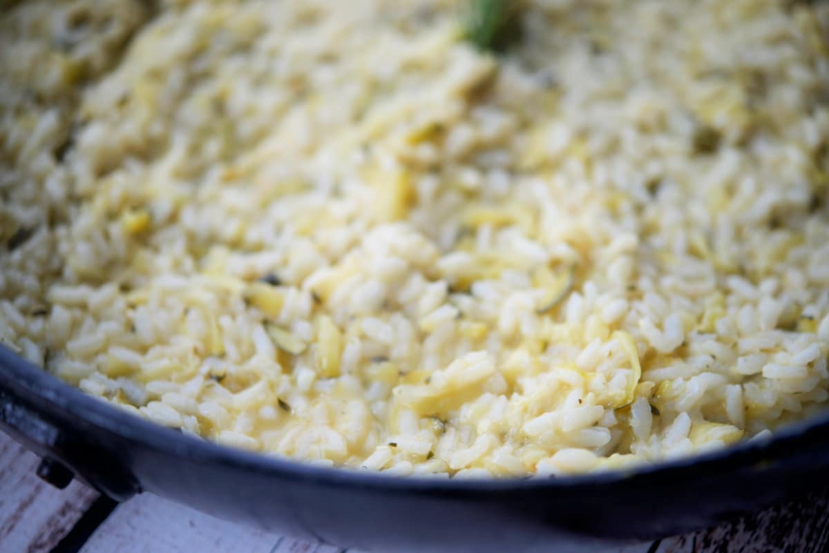 a close up of risotto with lemon and zucchini in a pan