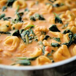 a close up of tortellini with spinach in a pink sauce