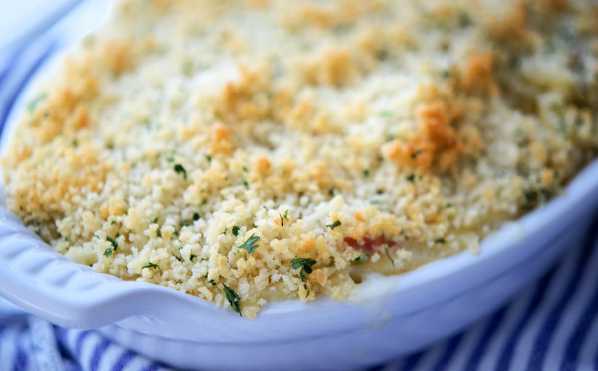 a close up of a white baking dish with breadcrumbs on top of mac and cheese