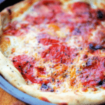 deep dish pizza with tomatoes in a pan