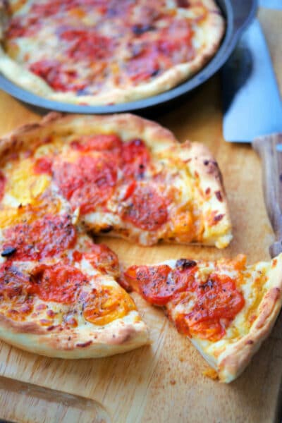 deep dish pizza with roasted grape tomatoes on a cutting board