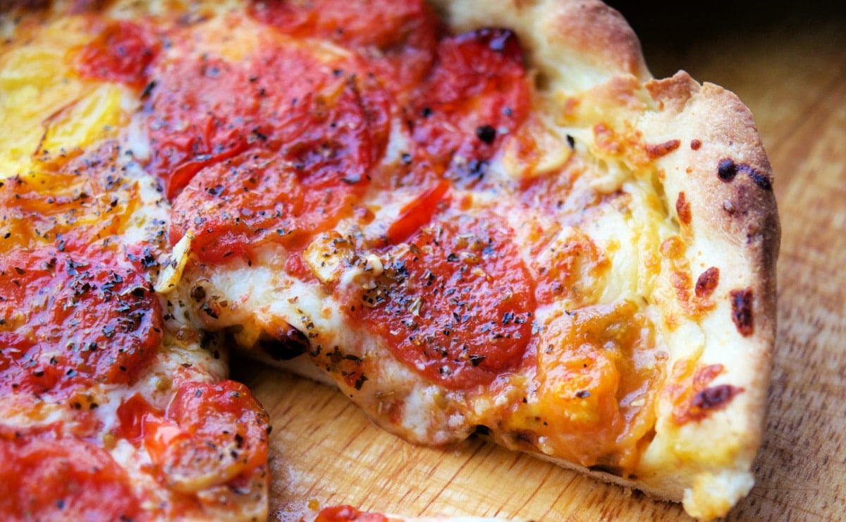 pizza on a wooden cutting board with roasted tomatoes
