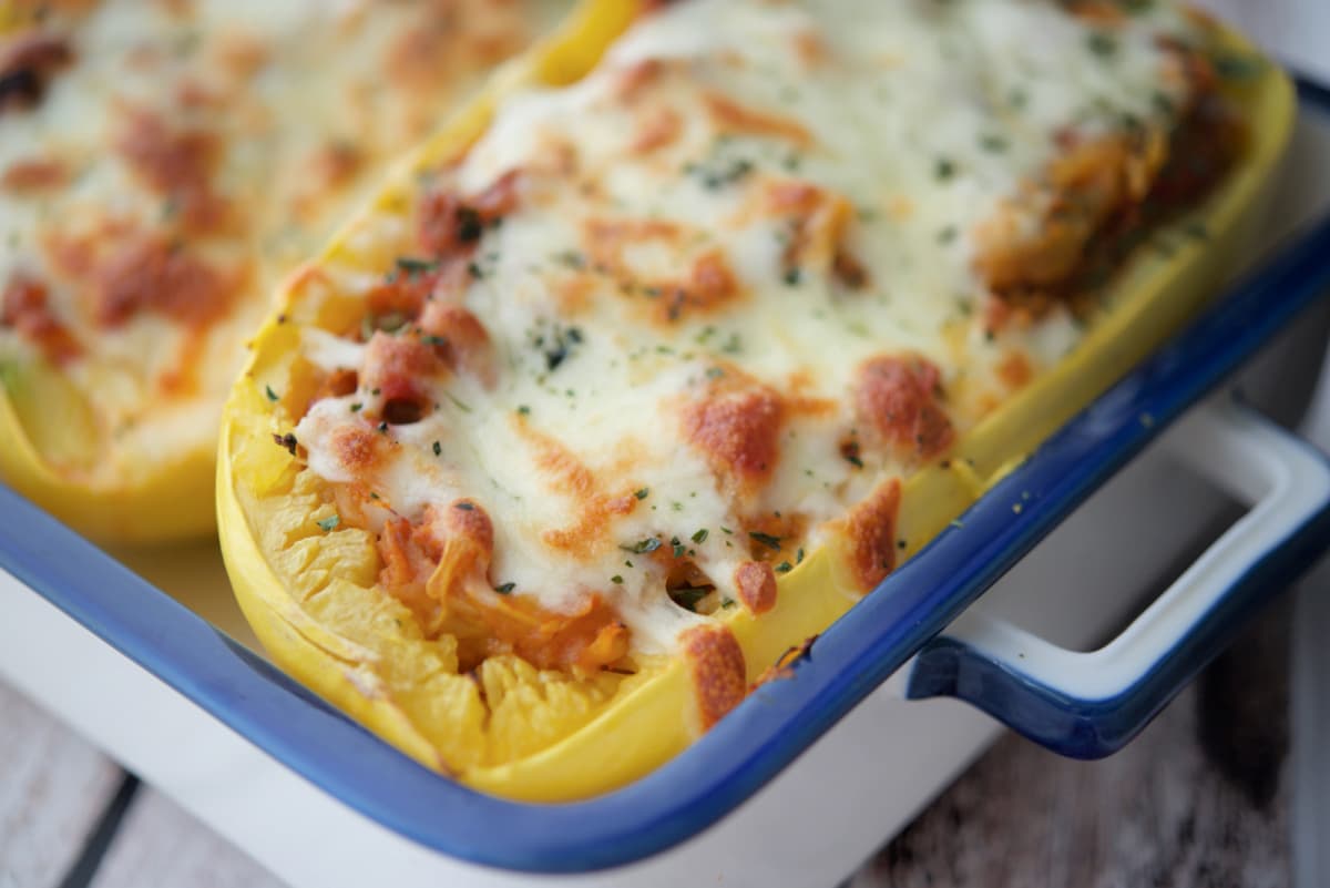 a close up of spaghetti squash cut in half stuffed with sausage bolognese