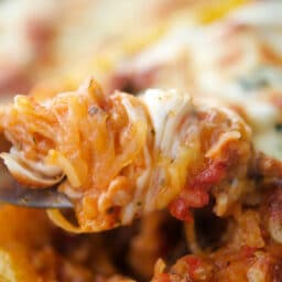 a close up of cooked spaghetti squash on a fork with sausage bolognese