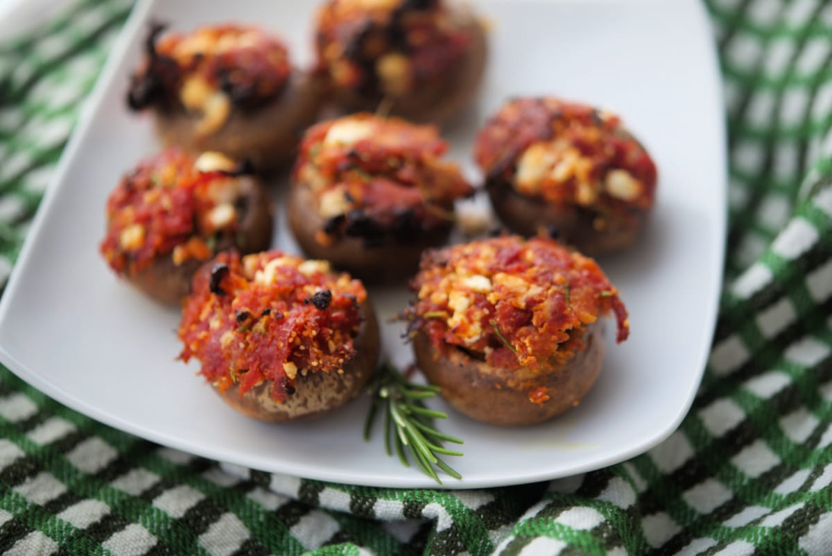 a plate of stuffed mushrooms with sun dried tomatoes