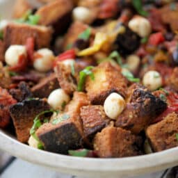 a close up of bread salad in a wooden bowl