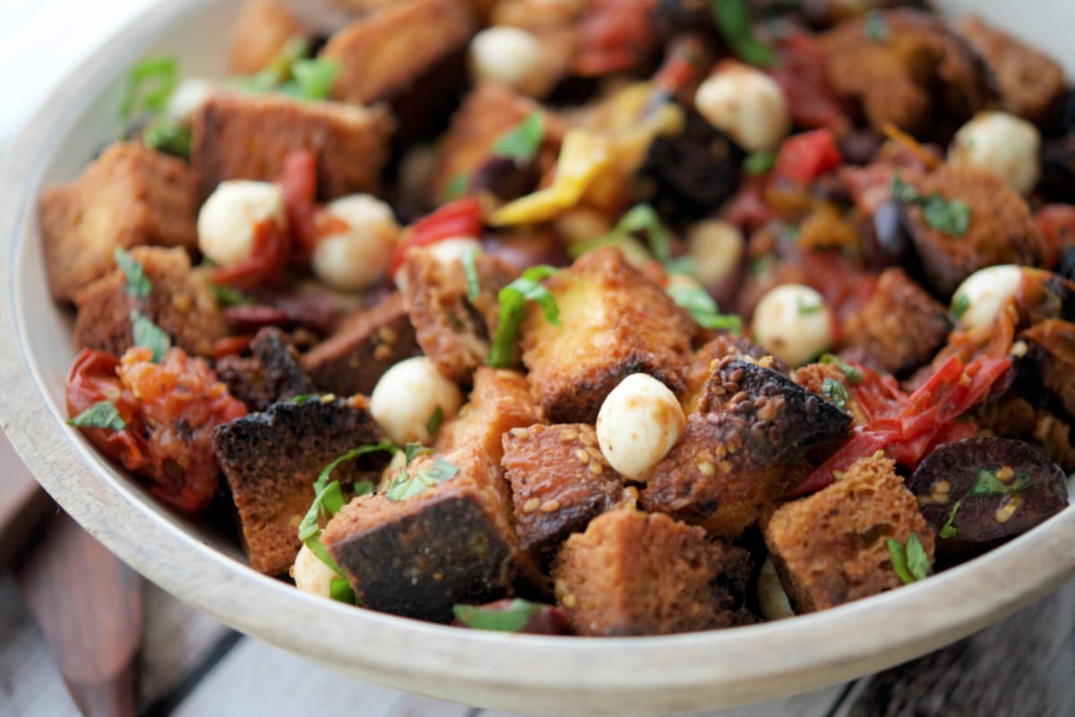 a close up of bread salad in a wooden bowl