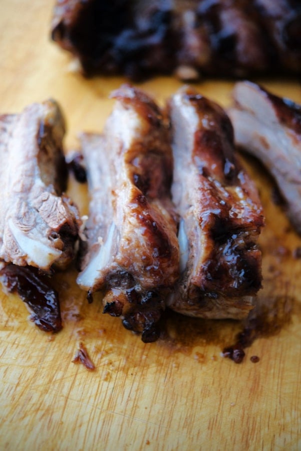 individual spareribs with bbq sauce on a wooden cutting board