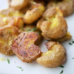 a close up of smashed potatoes on a white plate