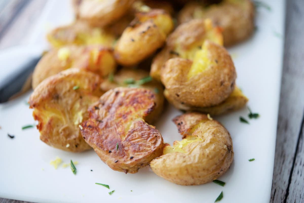 a close up of smashed potatoes on a white plate