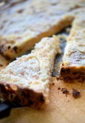 a piece of an apple pie tart cut out on a wooden board