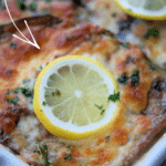 eggplant francaise with sliced lemons in a white dish